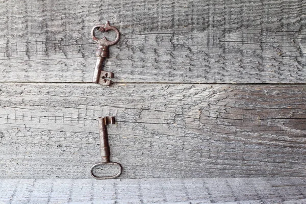 Old iron keys.  A pair of old keys on a wooden background.
