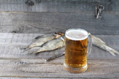 Bir kupa light bira ve ahşap arka plan üzerinde Kuru balık.