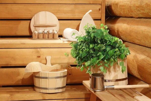 Fresh birch broom on the wooden bucket and bath accessories in the sauna.