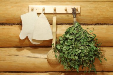 Geleneksel sauna aksesuarları duvarda asılı.