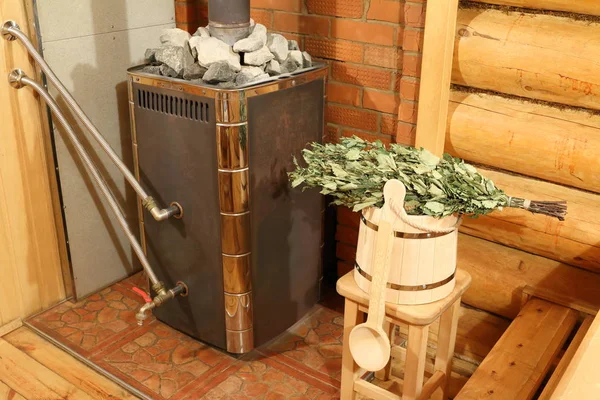 Rus hamamının içi. Bir kova huş süpürgesi, bir odun sobası ve sauna için diğer aksesuarlar Rus hamamının buhar odasında..