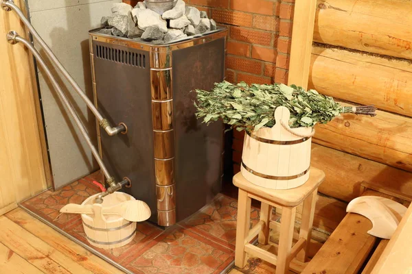 The interior of the Russian bath. A bucket with a birch broom, a wood stove and other accessories for the sauna are in the steam room of the Russian bath.