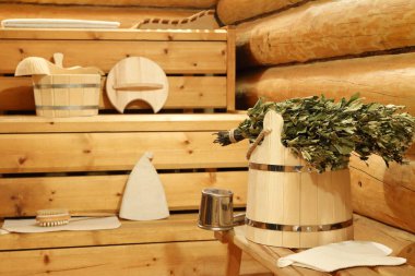 Huş süpürge saunada tahta kova ve banyo aksesuarları üzerinde kuru.