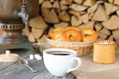 Huş ağacı bir yığın arka plan karşı ahşap masada samovar siyah çay bir fincan.