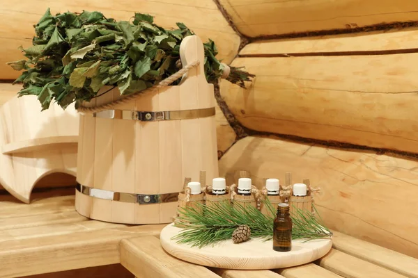 Yeşil çam dalının yanında sauna için gerekli yağı içeren şişeler. Doğal aromaterapi ve spa tedavisi kavramı.