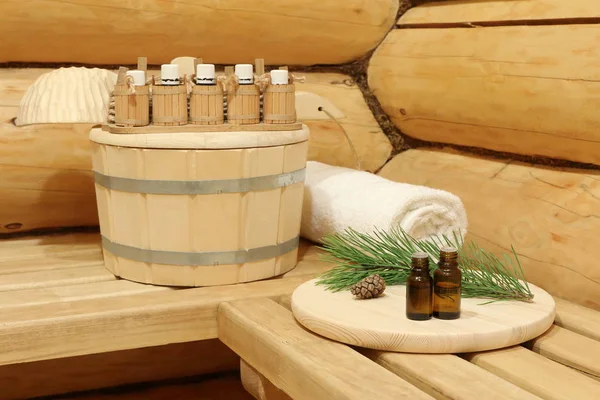 Yeşil çam dalının yanında sauna için gerekli yağı içeren şişeler. Doğal aromaterapi ve spa tedavisi kavramı.
