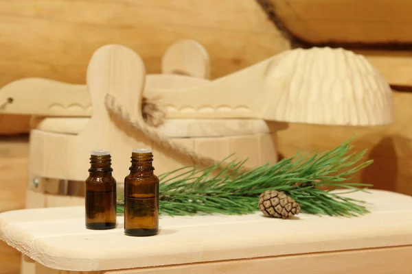 Yeşil çam dalının yanında sauna için gerekli yağı içeren şişeler. Doğal aromaterapi ve spa tedavisi kavramı.