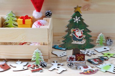 Still life from bright Christmas and New Year decorations and crate. Composition of bright Christmas and New Year decorations made of plywood and fabric on a wooden background.  clipart