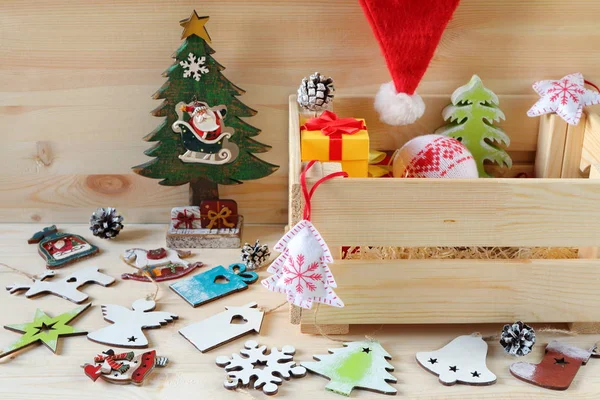 Still life from bright Christmas and New Year decorations and crate. Composition of bright Christmas and New Year decorations made of plywood and fabric on a wooden background.