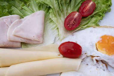 Yumurta, peynir, marul, domates ve hindi jambonlu sağlıklı bir kahvaltı. Taze sebzeler ve proteinlerle dengeli yemek, besleyici yiyecekler için diyet gıda konsepti.