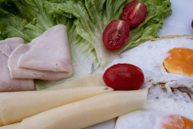 Yumurta, peynir, marul, domates ve hindi jambonlu sağlıklı bir kahvaltı. Taze sebzeler ve proteinlerle dengeli yemek, besleyici yiyecekler için diyet gıda konsepti.