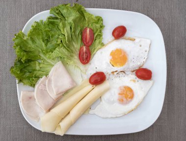 Yumurta, peynir, marul, domates ve hindi jambonlu sağlıklı bir kahvaltı. Taze sebzeler ve proteinlerle dengeli yemek, besleyici yiyecekler için diyet gıda konsepti.