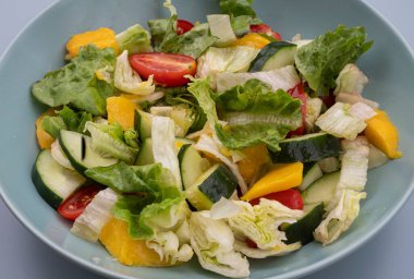 Marullu, salatalıklı, kiraz domatesli ve mavi kaseli renkli salata. Sağlıklı vejetaryen yemeği, organik taze sebzeler, beslenme konsepti, yakın çekim yüksek çözünürlüklü fotoğraf..