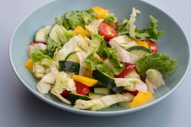 Marullu, salatalıklı, kiraz domatesli ve mavi kaseli renkli salata. Sağlıklı vejetaryen yemeği, organik taze sebzeler, beslenme konsepti, yakın çekim yüksek çözünürlüklü fotoğraf..