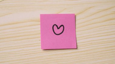 Pembe yapışkan bir nota basit bir kalp çiziyor.
