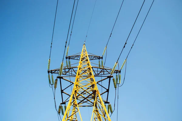 Mavi gökyüzüne karşı yüksek voltajlı elektrik kulesi