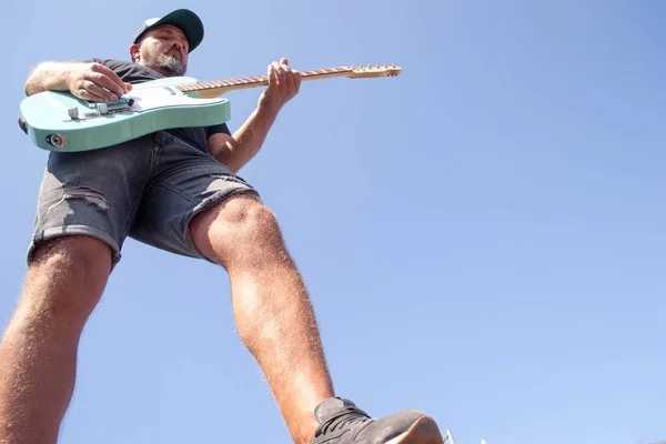 Adam açık havada elektro gitarda rock çalıyor.