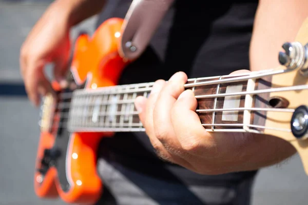 Adam dışarıda turuncu elektro gitar çalıyor.