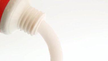 Beyaz arka plan, tıbbi, kozmetik ya da cilt ürünlerinden oluşan bir tüpten beyaz krem çıkıyor. Kapat.