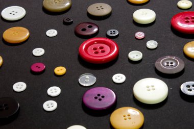 Bu siyah arkaplandaki renkli dikiş düğmelerinin fotoğrafı.