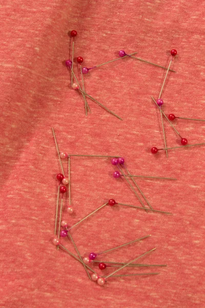 This is a photograph of sewing pins placed on fabric