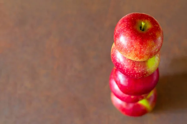 Tower of five fresh red apples on the rusty metal background. Closeup, selective focus