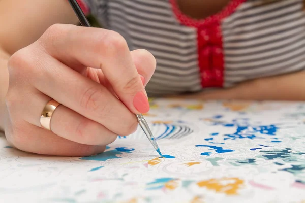 Girl draws with a brush painting by numbers on canvas. Picture by numbers. Drawing on canvas. Creative hobby. Painting for beginners. The concept of a hobby. Closeup, selective focus