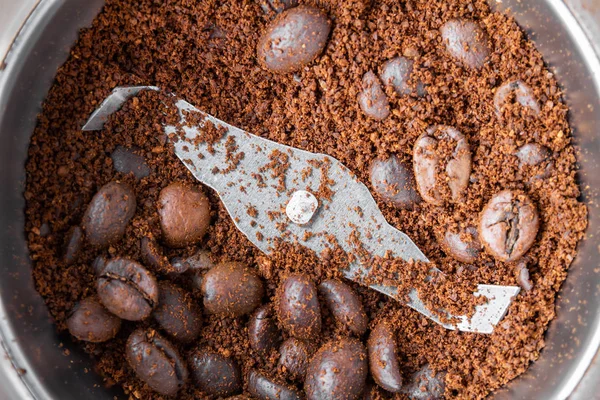 Metal elektrikli kahve değirmeni. Kahve değirmeni bir tarafı, başka bir zemin ile kahvenin bütün taneleri ile. Çekim, seçici odak, üst görünüm