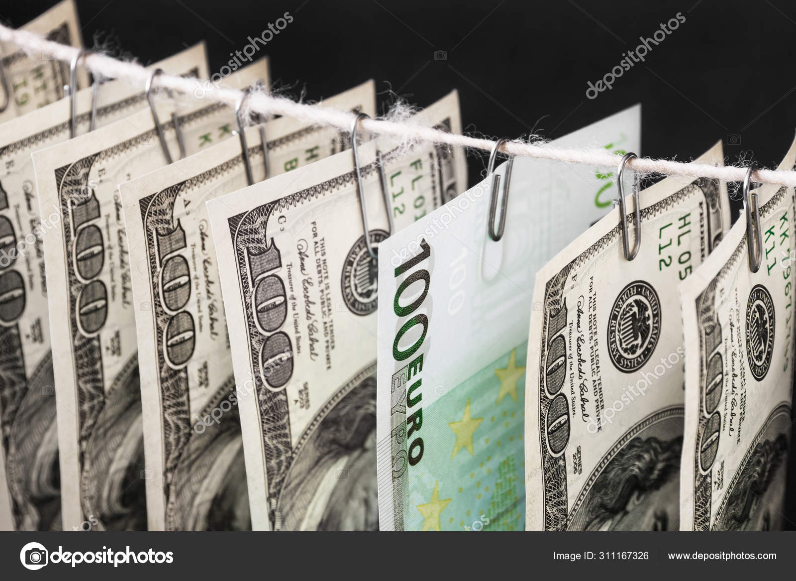 一百美元钞票和一百欧元钞票的一部分挂在黑暗背景的绳子上的文书夹子上。 闭锁，有选择的重点——图库图片© marketlan #311167326
