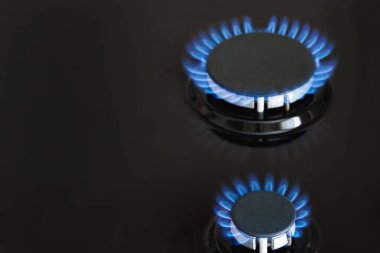 İki gaz ocağı, karanlık sobada mavi gazla yanıyor. Yakın çekim, seçici odaklanma