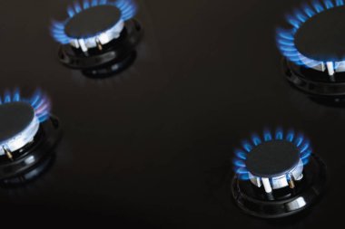 Dört gaz ocağı, karanlık sobada mavi gazla yanıyor. Yakın çekim, seçici odaklanma
