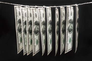 Yüz dolarlık banknotlar karanlık arka plandaki bir ipte asılı duruyor. Yakın çekim, seçici odaklanma