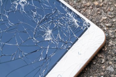 Kırık mavi ekranlı akıllı telefon asfaltta yatıyor. Yakın çekim, seçici odaklanma