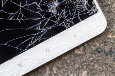 Kırık mavi ekranlı akıllı telefon asfaltta yatıyor. Yakın çekim, seçici odaklanma