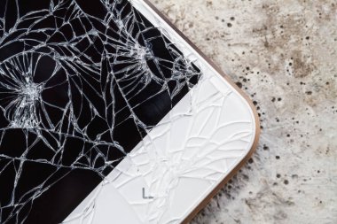 Ekran ekranı kırık akıllı telefon betonun üzerinde duruyor. Yakın çekim, seçici odaklanma