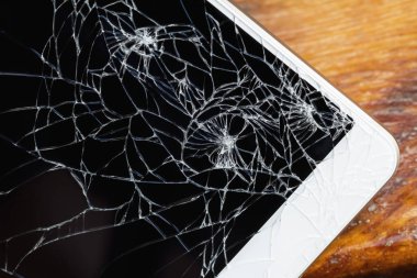 Ekranı kırık akıllı telefon ahşap bankta yatıyor. Yakın çekim, seçici odaklanma