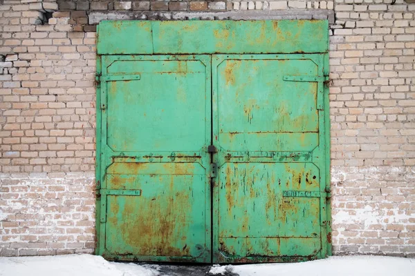 Old green rusty garage doors on the wall of sand-lime bricks — Stock Photo, Image