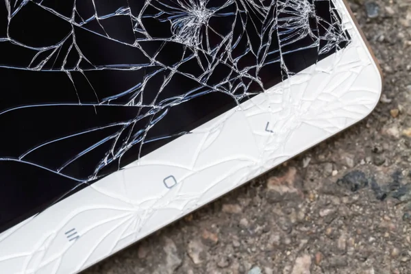 Kırık mavi ekranlı akıllı telefon asfaltta yatıyor. Yakın çekim, seçici odaklanma