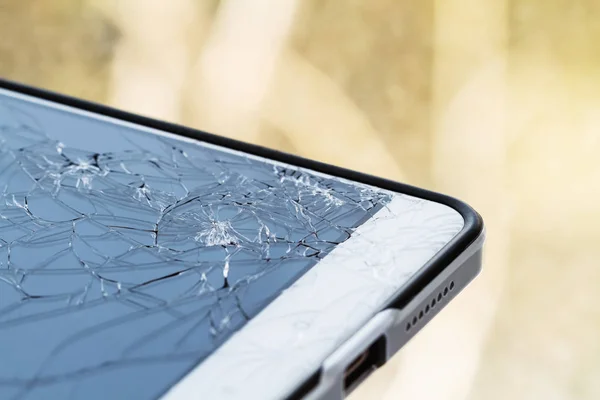 Smartphone with broken screen. Damaged phone glass. Closeup, yellow background, selective focus