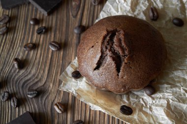 Kahve çekirdekleri ve çikolatalı parşömen üzerine ev yapımı çikolatalı kek. Koyu ahşap zemin, yakın plan, üst manzara