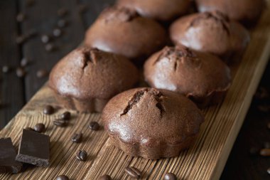 Bir grup ev yapımı çikolatalı kek, içinde kahve çekirdekleri ve çikolata parçaları olan tahta bir tahtanın üzerinde. Koyu ahşap arka plan, yakın plan, seçici odak