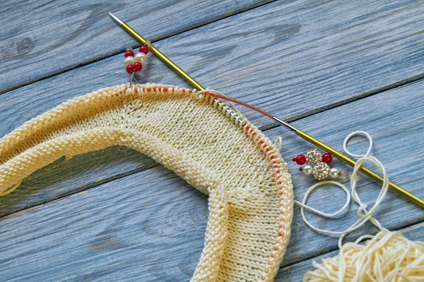 Sarı örülmüş raglan ya da mavi ahşap arka planda kazak. Çalışmalar devam ediyor. Yakın çekim.