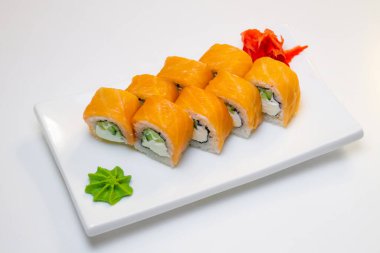 Beyaz bir tabakta somon, salatalık, peynir ve wasabi ruloları.