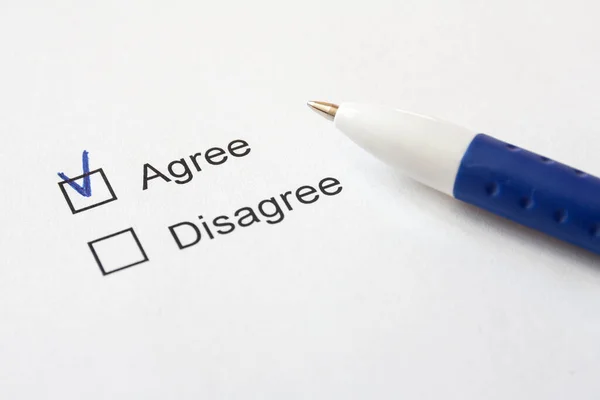 Tercihleri olan beyaz bir kağıt. Katılıyorum, anlaşmazlık ve mavi bir kalem. Seçici odak.