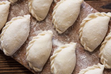 Vareniki, hamur tatlısı, un ahşap bir tahtada pierogi pişirmeye hazır. Geleneksel Ukrayna yemeği. Seçici odak