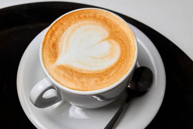Bir fincan kahve. Siyah-beyaz arka planda beyaz bardakta kalp desenli Latte.