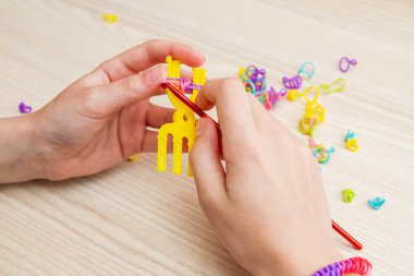 Lastik bantlı dokuma. Dokuma tezgahıyla lastik bantlar örüyorlar. Lastik bileklik takan bir kızın elleri..