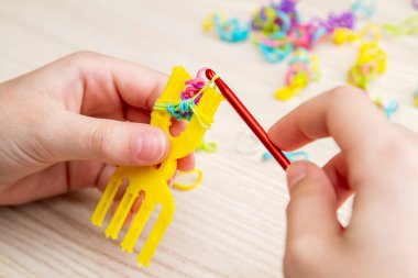 Lastik bantlı dokuma. Dokuma tezgahıyla lastik bantlar örüyorlar. Lastik bileklik takan bir kızın elleri..