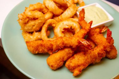 Kral karidesleri sade ve baharatlı ekmek kırıntılarıyla kaplanmış ve bol yağda kızartılmış. Sarımsak sosuyla servis edilmiş. Yakın çekim, seçici odaklanma