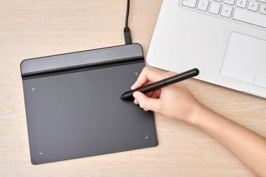 Kız kalemle grafik tabletine resim çiziyor. Yakın çekim, seçici odaklanma